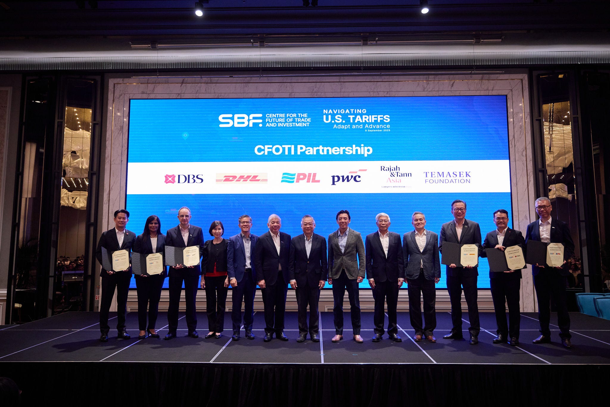 Group photo of CFOTI partner representatives holding certificates; from left to right: James Chan, Senior Director, Temasek Foundation; Kala Anandarajah, Head, Competition & Antitrust and Trade, Rajah & Tann Singapore LLP; Frank Debets, Asia Pacific Customs and Trade Leader, PwC Singapore; Ng Bee Kim, CFOTI Committee Member; Kok Ping Soon, CEO, SBF; S. S. Teo, Chairman, SBF; Gan Kim Yong, Deputy Prime Minister and Minister for Trade and Industry; Jeffrey Siow, Acting Minister for Transport and Senior Minister of State for Finance; Gan Seow Kee, Chairman, CFOTI; Tan Chin Hwee, Vice Chairman, CFOTI; Chee Yaw Chek, Vice President, Commercial, DHL Express (Singapore) Pte Ltd; Chen Ze Ling, Group Head of Corporate and SME Banking, DBS Bank; William Ng, Group Chief Financial Officer, Pacific International Lines