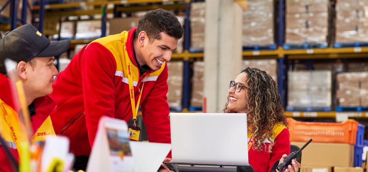 A female DHL employee is giving advice to her male colleagues at Teva Warehouse ground office.