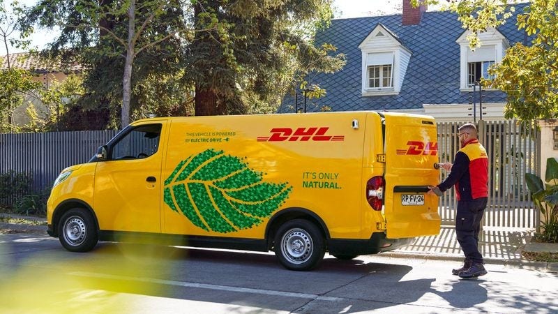 DHL delivery man unloading packages from sustainable shipping van