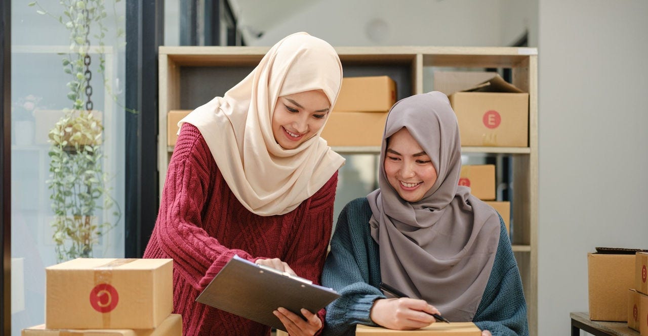 Friend muslim female two work business sme online shopping working on laptop computer with parcel box on desk at home, SME online business and delivery concept