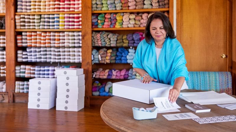 e-commerce shop owner reaches for shipping labels prepared for international shipping