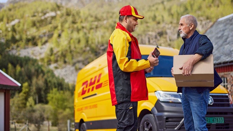 An elder male customer is talking to a smiling, male DHL employee. 