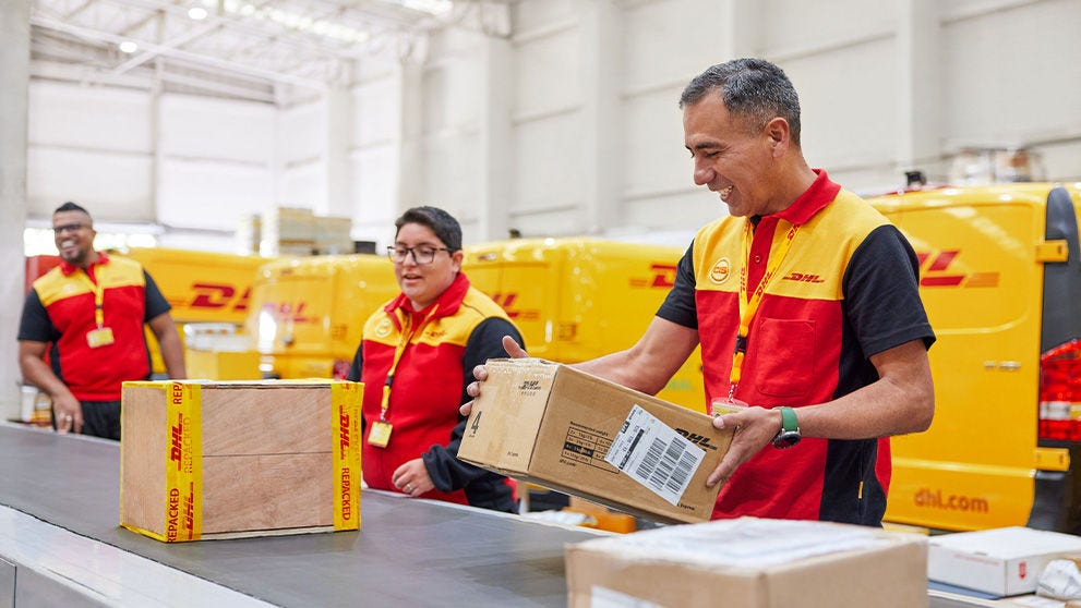 tři zaměstnanci DHL nakládají balíky