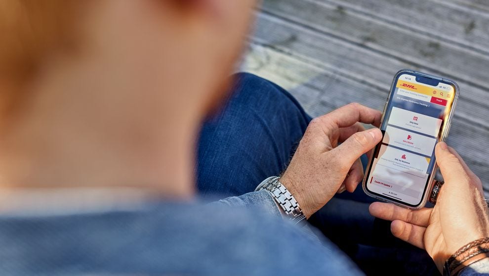 ชายหนุ่มใช้โทรศัพท์เพื่อเรียนดูวิธีชําระเงินออนไลน์ด้วย DHL MyBill
