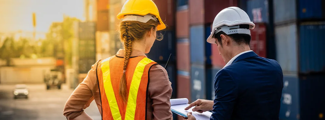 logistics tips man and woman in hard hearts looking at clipboard