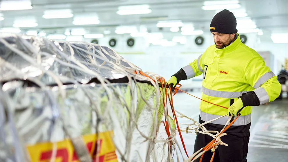 Empleado de DHL atando un palé de mercancías