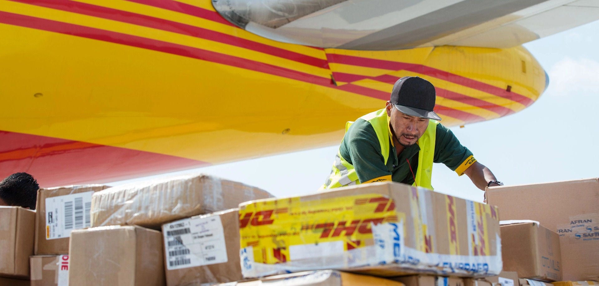 DHL工人在货机下方分拣待装机的跨境快件。