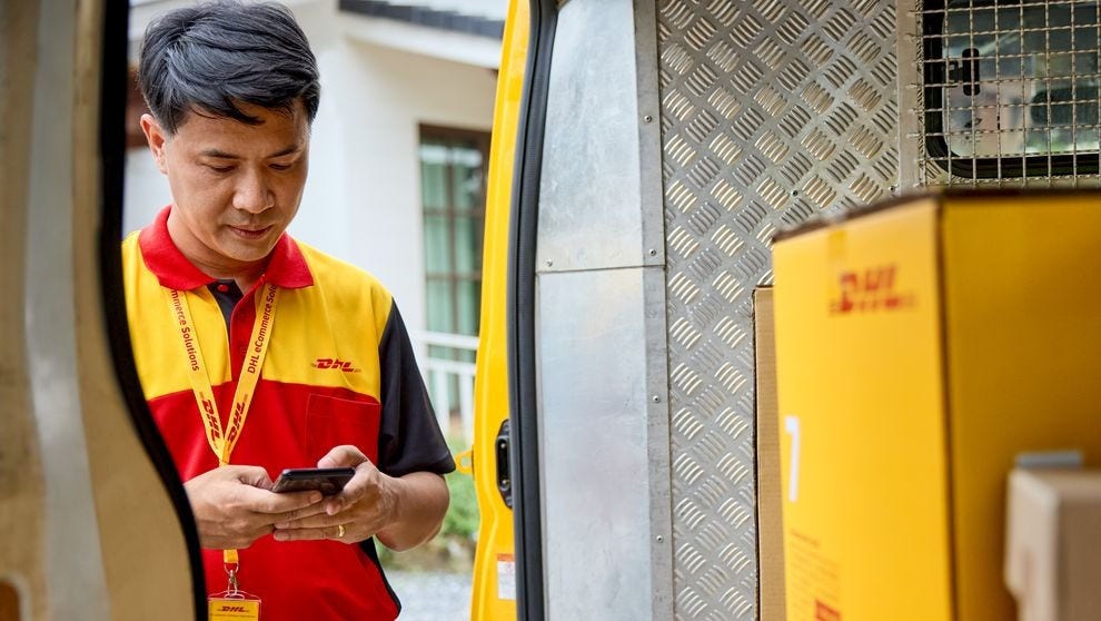 A DHL employee checking on his order in front of an open van.