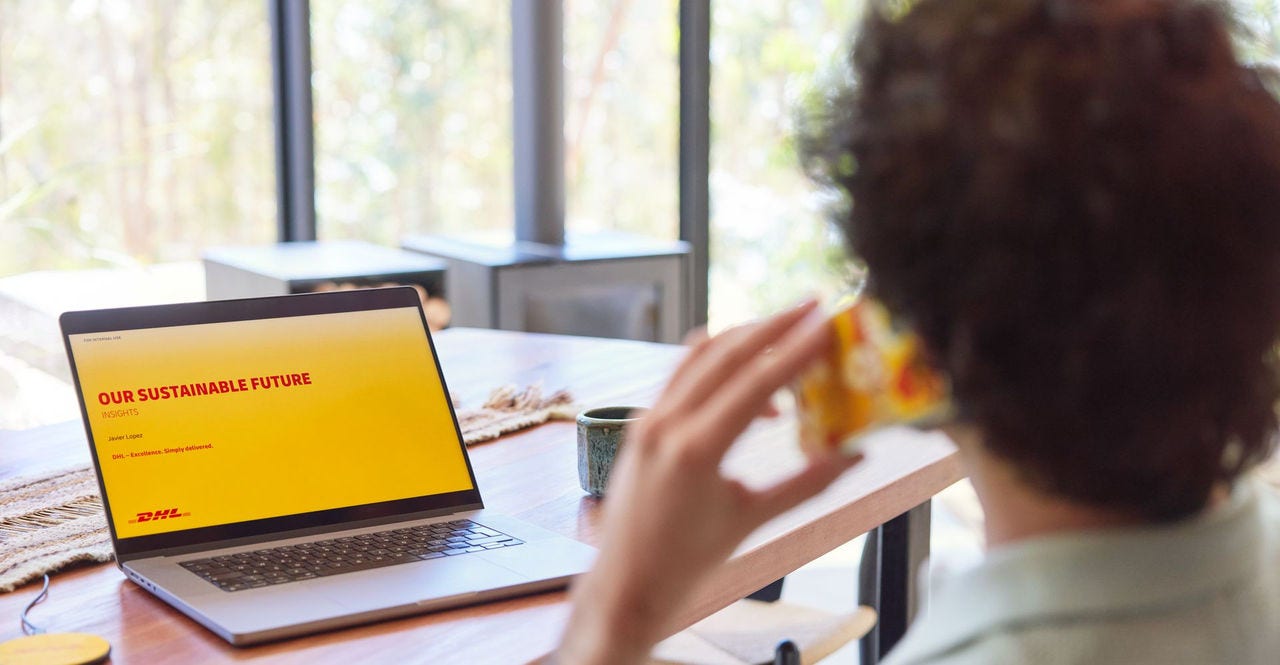 a young man using his laptop at home with the screen showing a slide on sustainable future