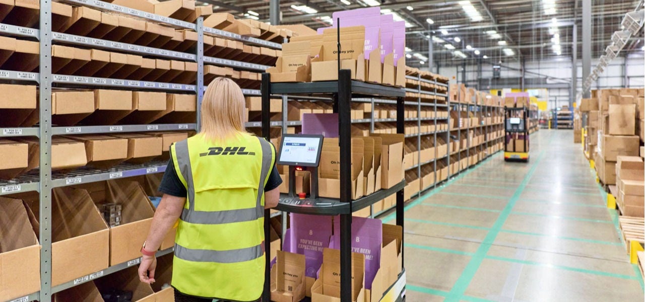 一名 DHL 员工从仓储货架上拣取货品。