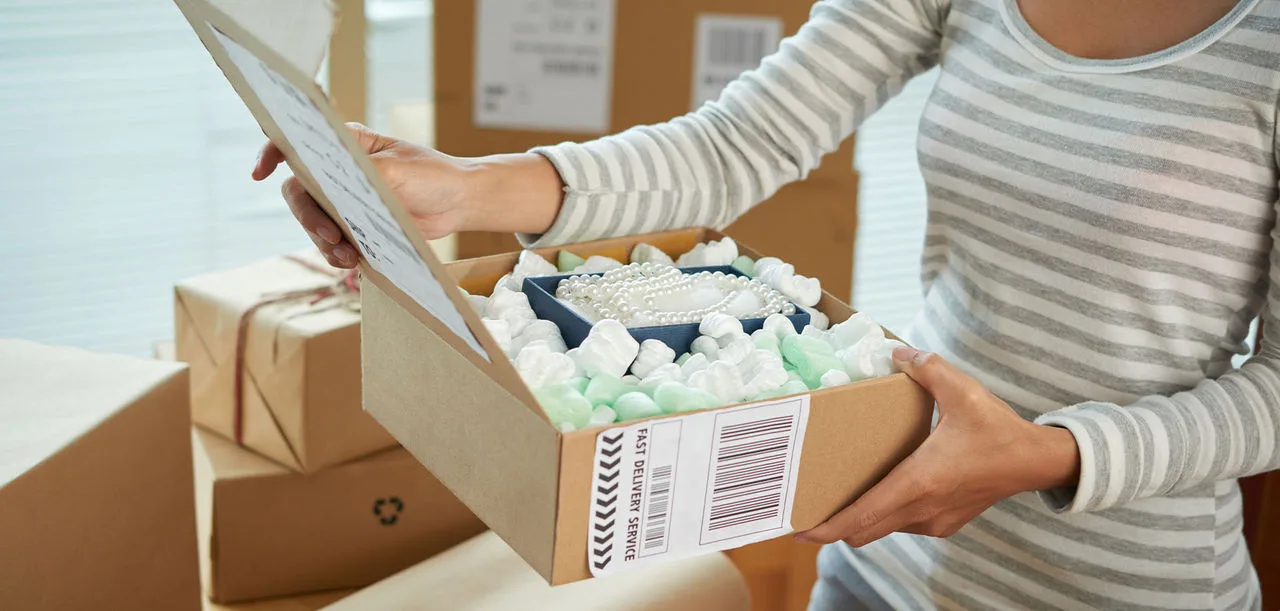 woman packing jewelry in brown box