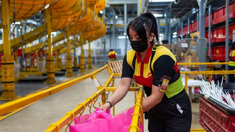DHL Express employee managing garment on hangers to streamline logistics in the fashion industry