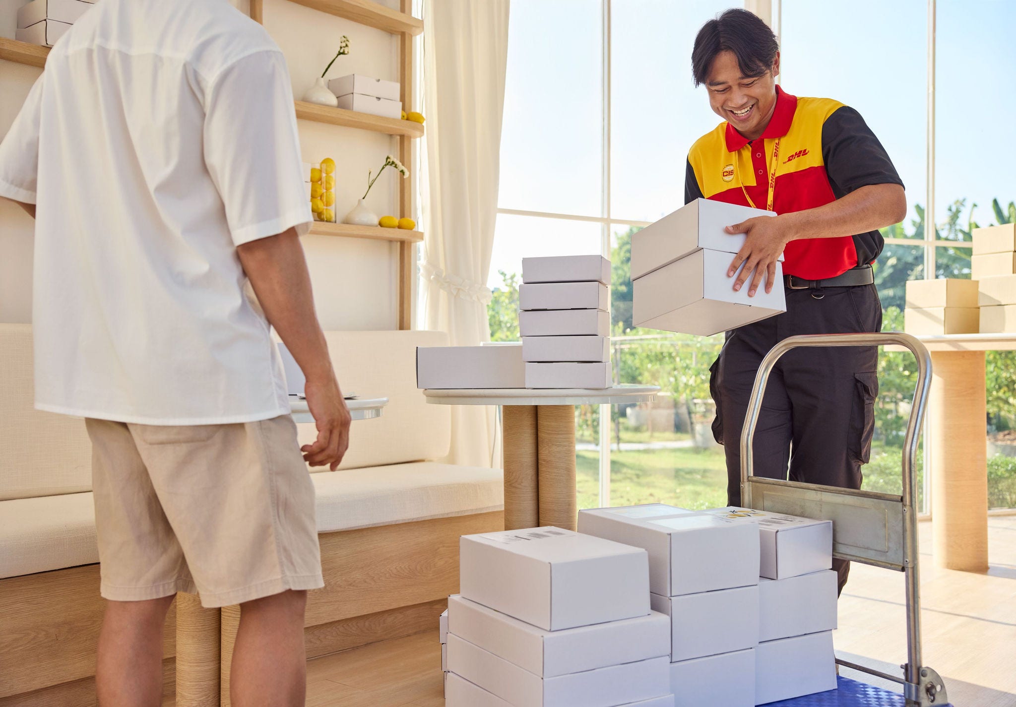 A male DHL employee is loading parcels for pickup on his handcart.