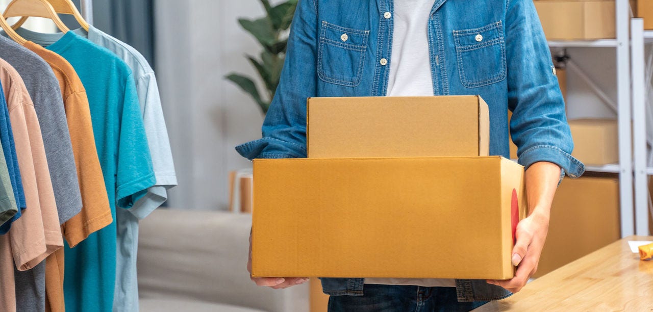 Small business owner holding sealed, labelled cardboard boxes ready to ship to customers