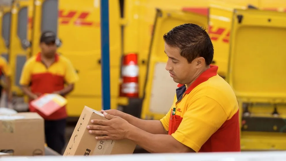 A DHL Express employee checking a label on a delivery box