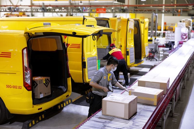 dhl workers sorting packages on a conveyor belt at a logistics facility