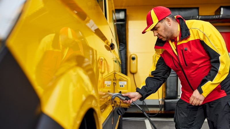 dhl express employee recharging an electric van via a wall outlet