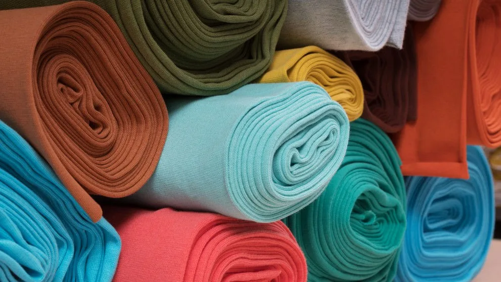 multiple rolls of colorful garments to be shipped overseas