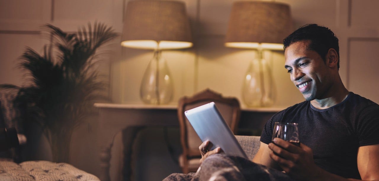 Man reading on a table with a glass of red wine