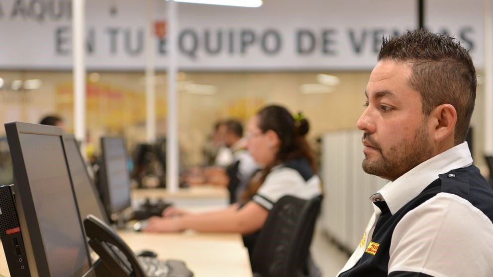 DHL staff managing international shipments with computer software