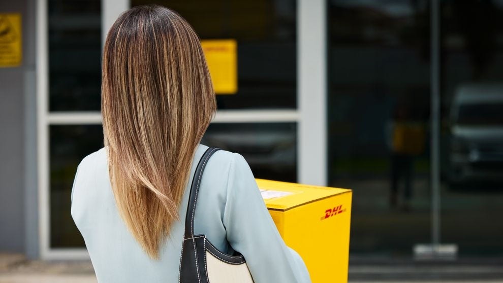 ลูกค้าหญิงคนหนึ่งกําลังเดินทางไปส่งพัสดุ DHL Express ที่ DHL ServicePoint
