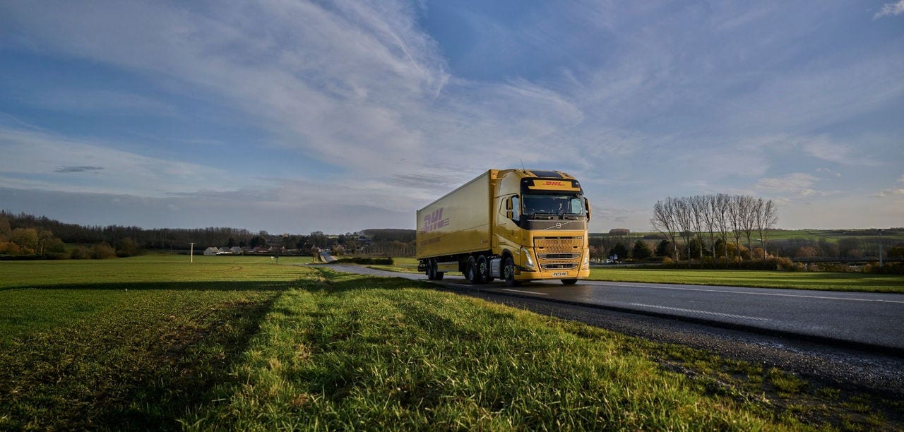 DHL nákladné auto jazdí cez vidiek s poliami