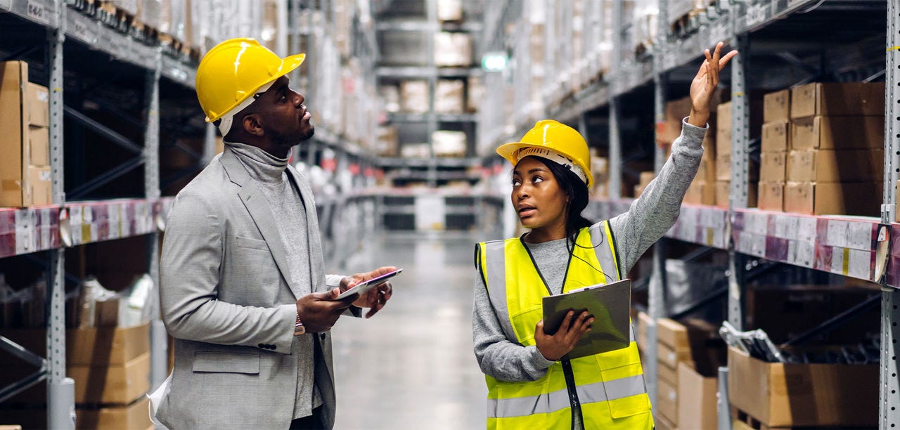 man and woman in hard hats in a warehouse