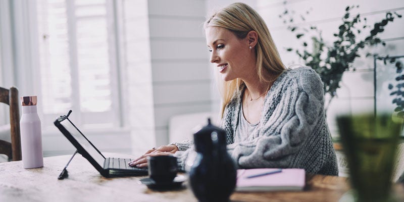 Woman sitting at desk with laptop, tea and water bottle