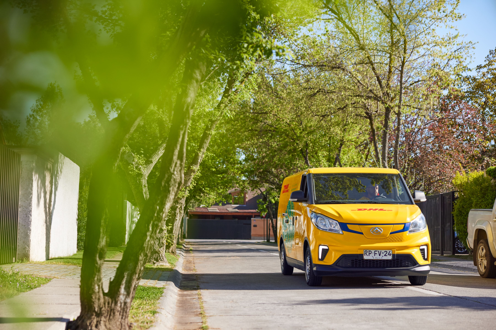 a DHL van drives through a green neighbourhood
