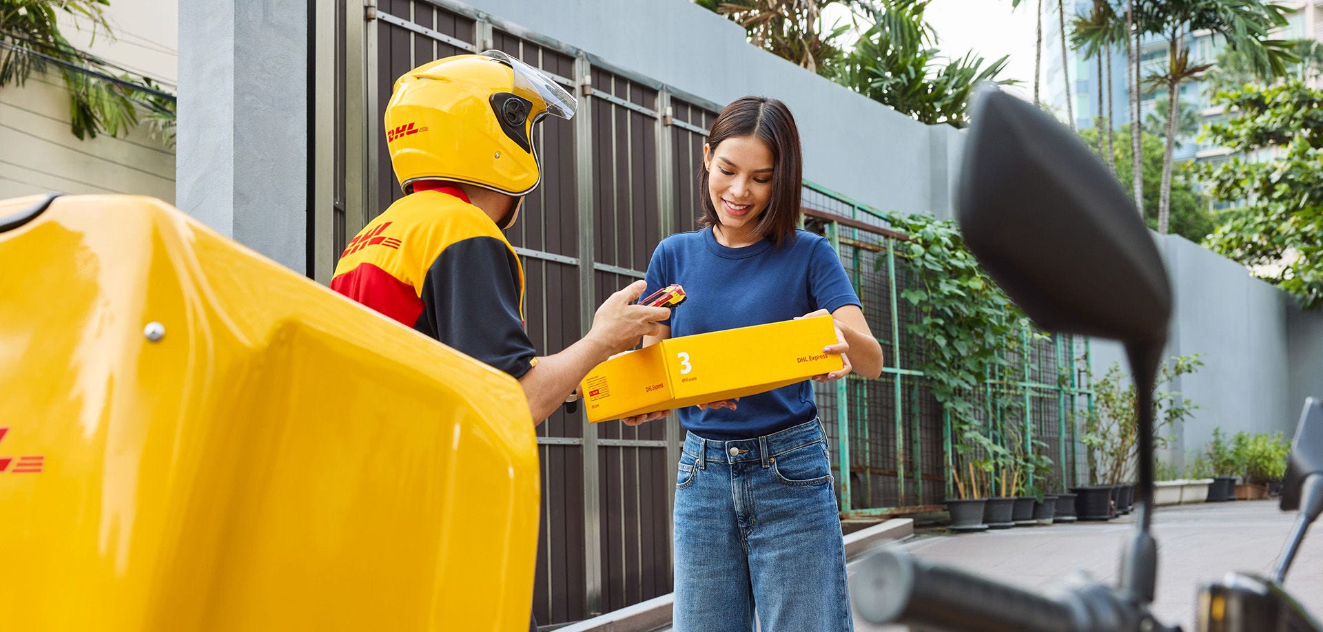 Woman taking DHL package from employee delivering it
