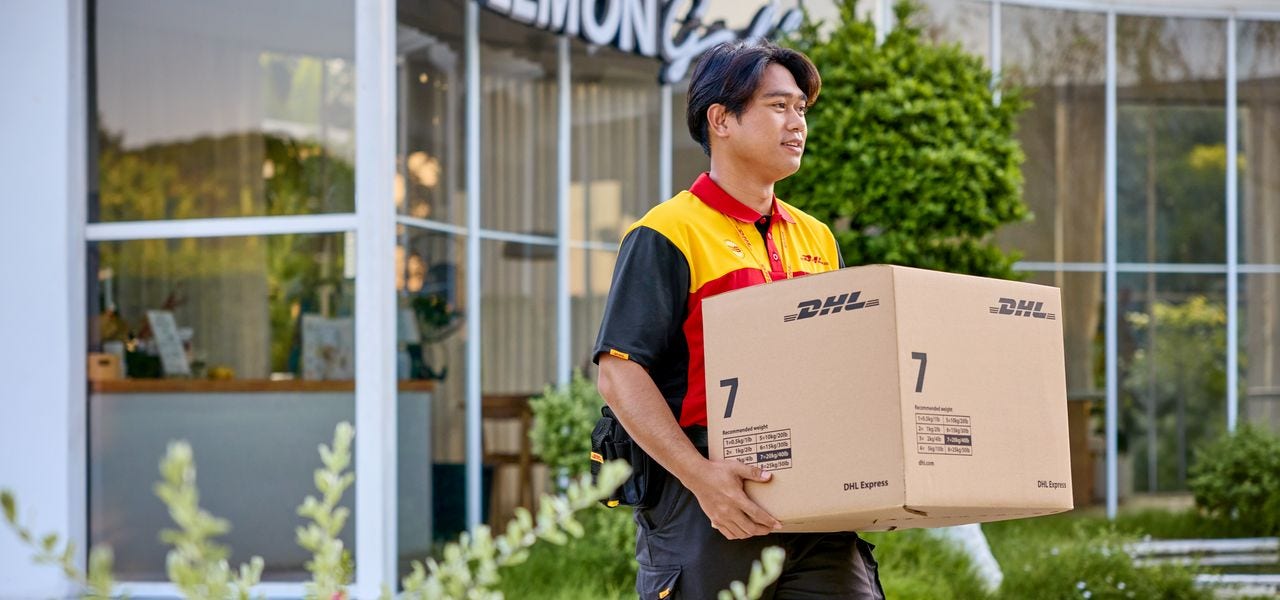 A male DHL employee who just picked up a sustainable brown DHL express parcel.