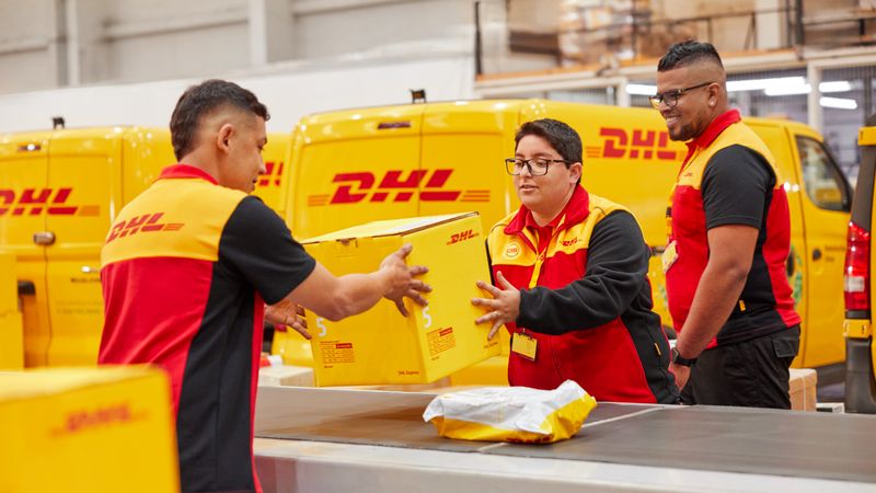 dhl express employees handing off a parcel at a dhl express hub