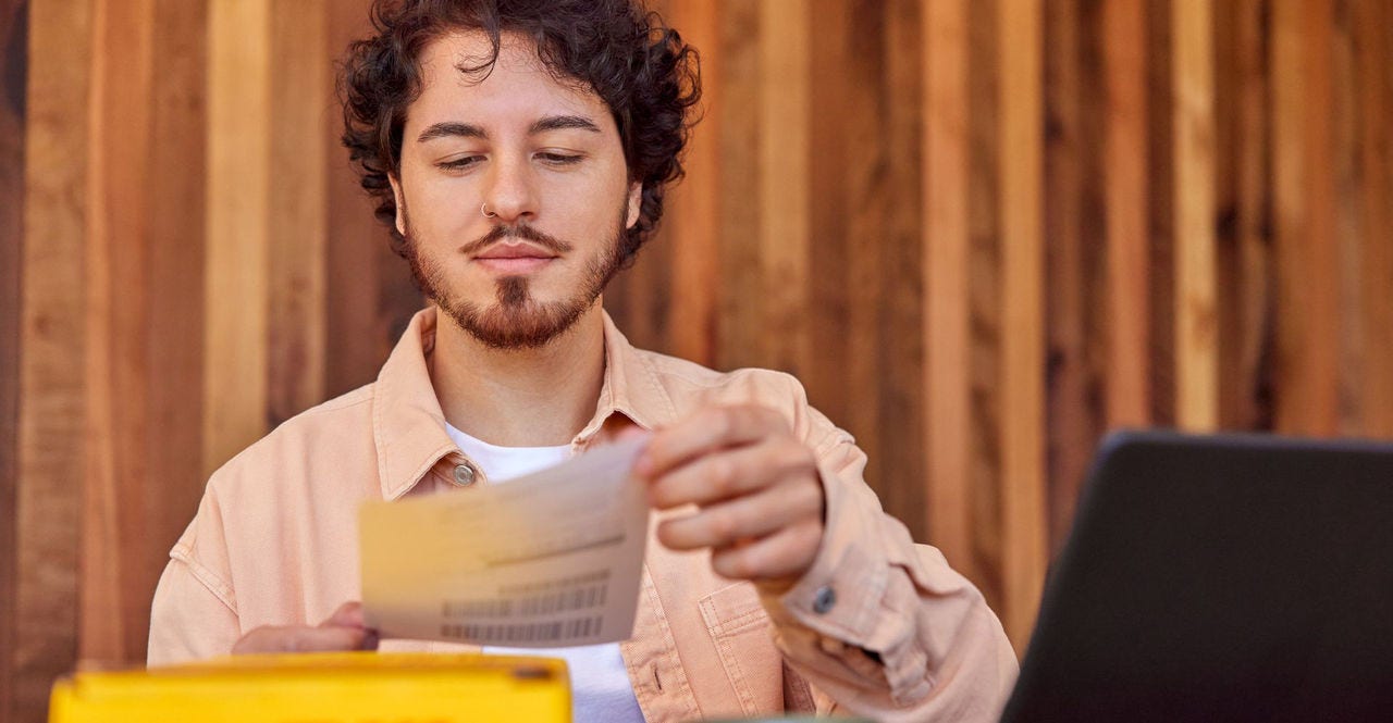 male DHL customer attaching printed shipping label with insurance to his parcel