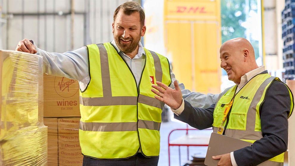 two men in hi vis vests looking at pallets