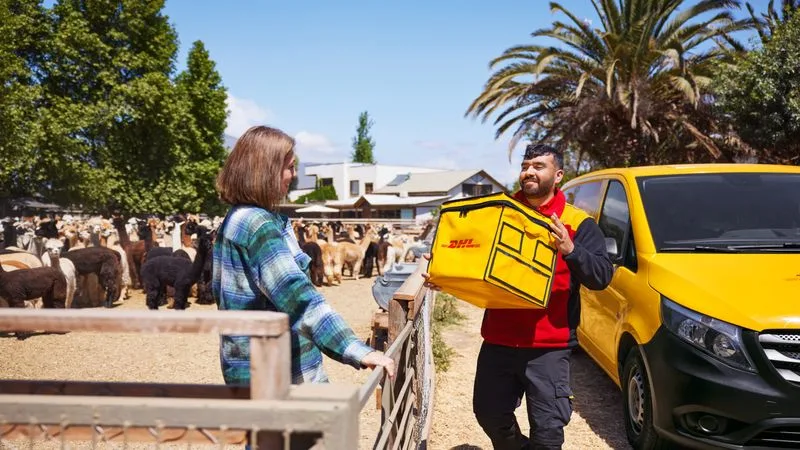 A DHL Express employee carrying a cooling box for e-commerce shipping