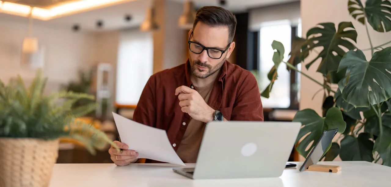 Man sitting in an office space, reviewing paperwork