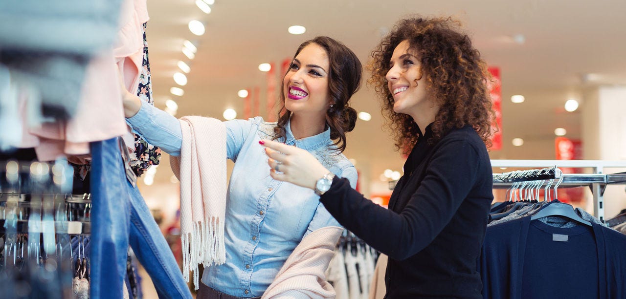 two women looking at a rack of clothing