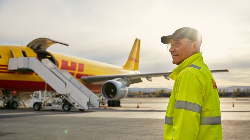 DHL employee standing in front of a cargo plane before air freight