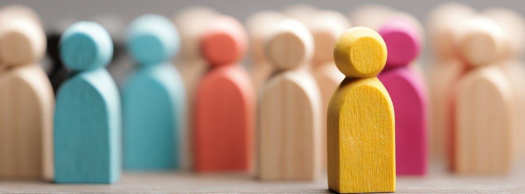 Colorful Wooden Figures Standing Out in a Crowd