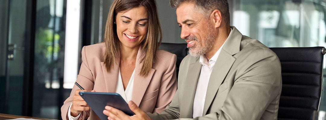 man and woman smiling at tablet screen
