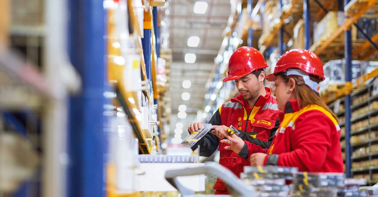 two dhl employees interacting at a warehouse while inspecting the goods