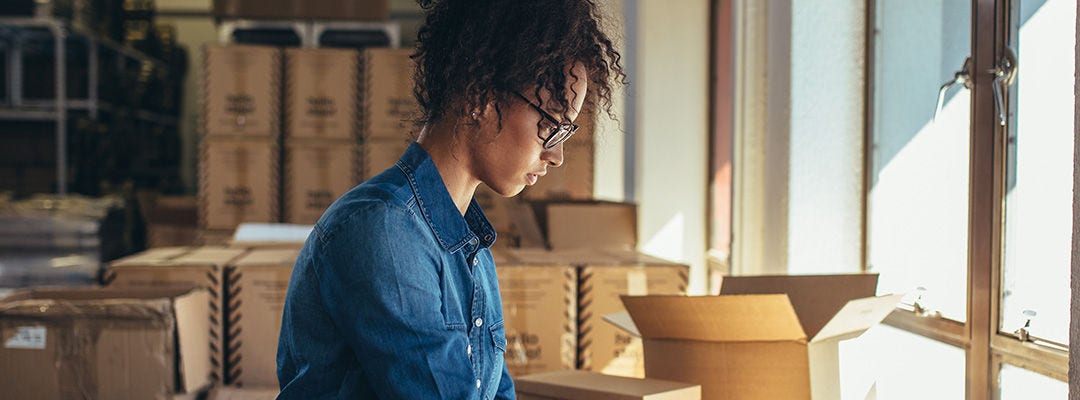 Female business owner working, packing the order for shipping to customer. 