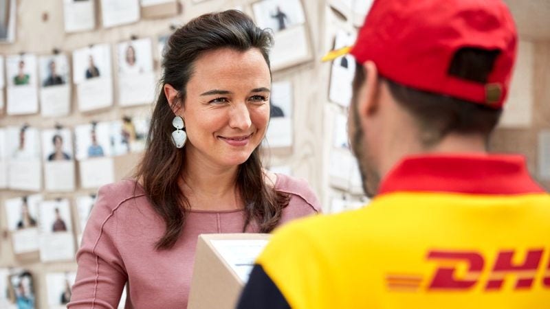 a dhl employee picks up a parcel from a customer