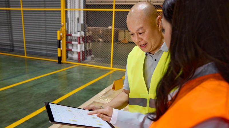 Two DHL Express employees using a tablet device in a warehouse