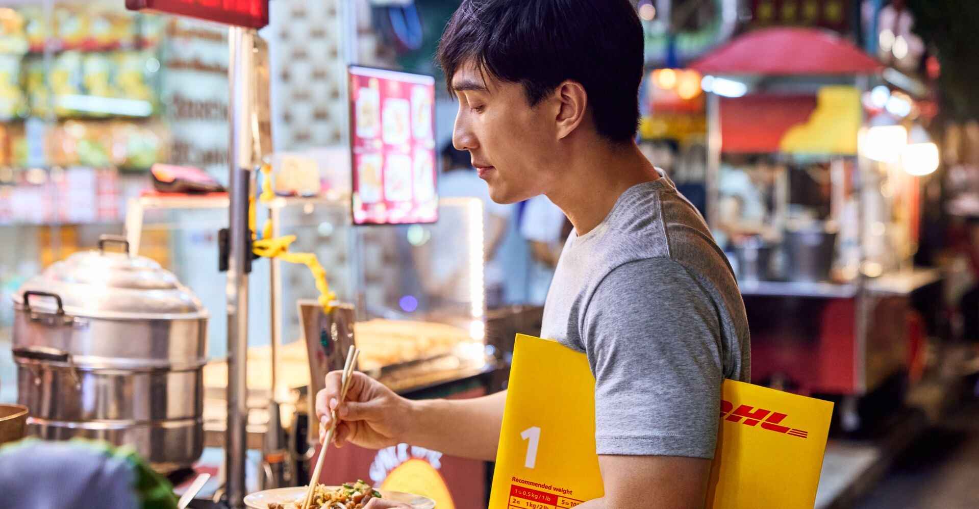 a man holding a dhl packing material, specifically a dhl envelope