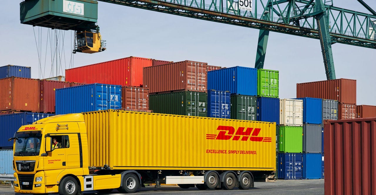 Seorang karyawan DHL memuat paket untuk diambil dengan gerobak tangannya.