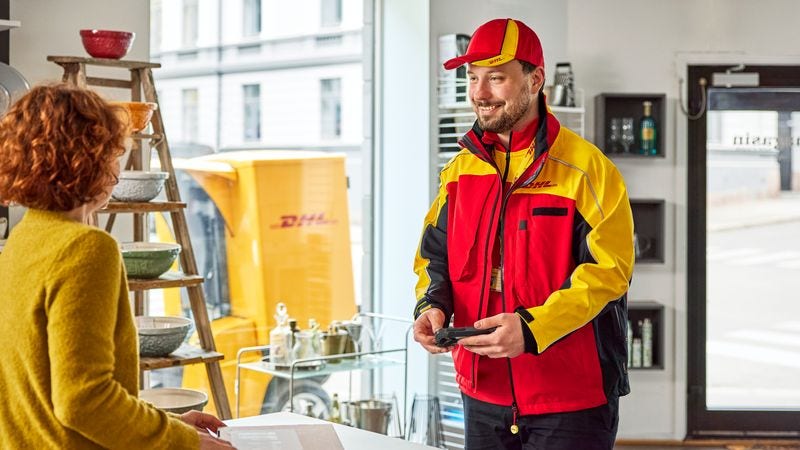 Seorang karyawan DHL laki-laki sedang mengantarkan paket ke pelanggan wanita di toko livestreaming-nya.