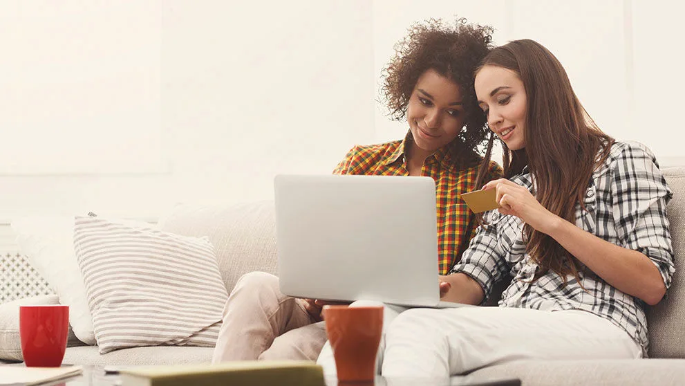 Deux femmes souriantes et regardant la carte de crédit