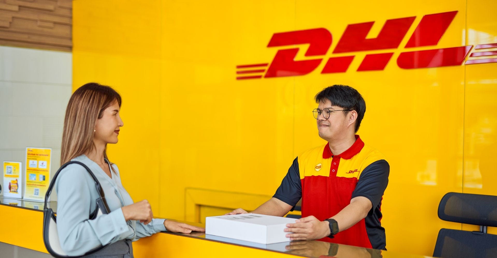 DHL Express employee at service counter attending to a visitor.