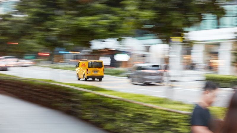 dhl express van driving on a street with blurred background
